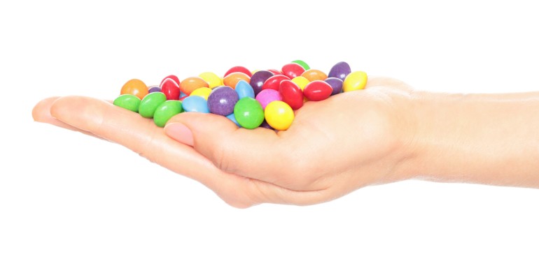 Woman hand holds lot of color candies, isolated on a transparent background, fast food concept