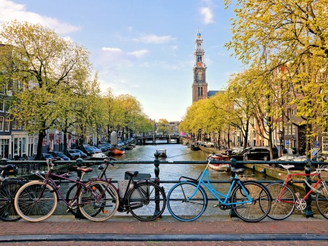 Bicycles lining a bridge over the canals of Amsterdam with church in background. Late day light. Netherlands.