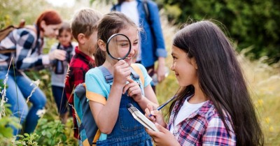 A group of small school children with teacher on field trip in nature, learning science.