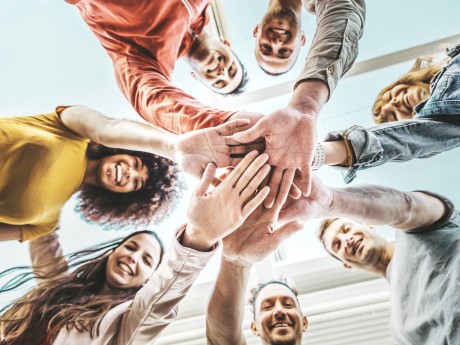 Group of young people stacking hands together outdoor - Community of multiracial international people supporting each other - Union, support and human resources concept