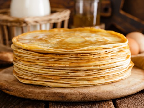 Homemade thin crepes with honey, pancakes on wooden rustic background